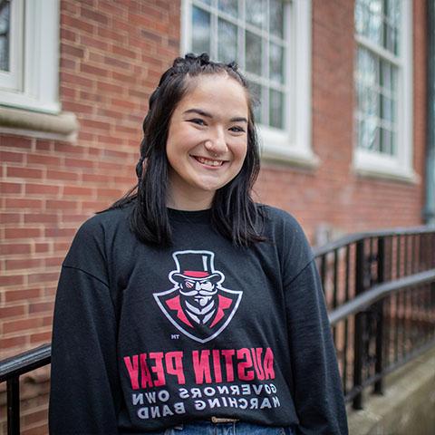 Austin Peay education student stands in front of a building. 